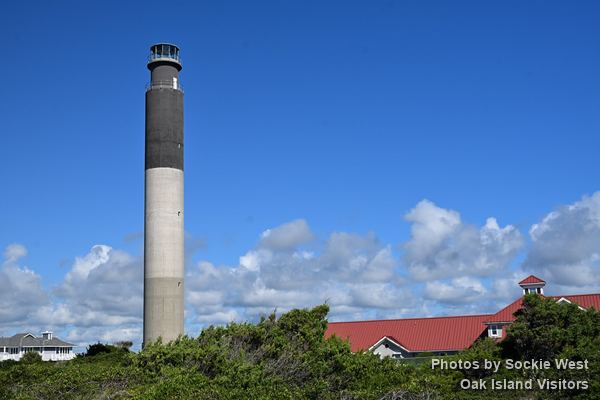 Oak Island Lighthouse beside the red roofs of the old Coast Guard station, Caswell Beach